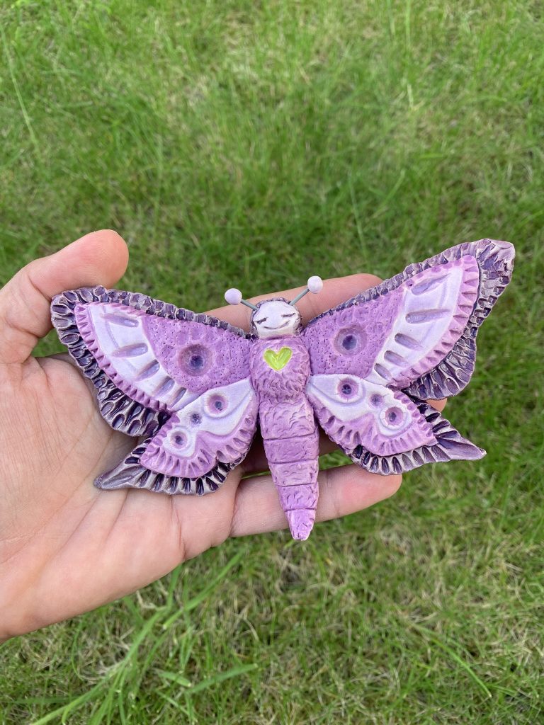 Whimsical tactile butterfly ceramic wall piece in purple tones with tiny cute antennas and plenty of texture
