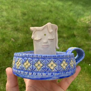 functional whimsical ceramic candle holder, with a kind face and textured mediterranean vibe base