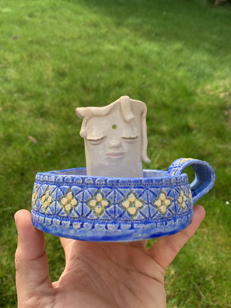 functional whimsical ceramic candle holder, with a kind face and textured mediterranean vibe base