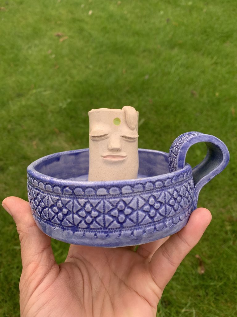 ceramic whimsical candle holder with a kind face and Mediterranean vibes textured base. It also has a handle